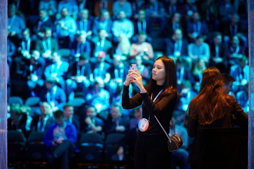 NIC 2020 Vision, en jente som tar selfie med publikum i bakgrunnen